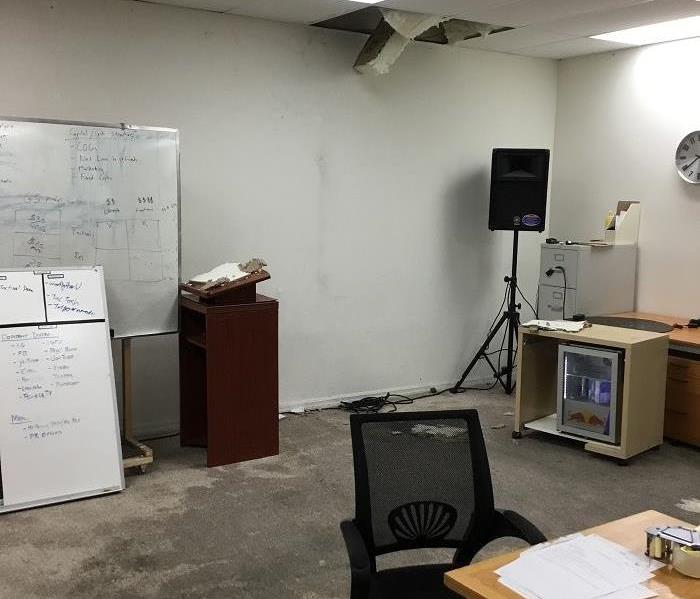 Office space with wetted carpet from a major pipe leak, bursting from one of the ceiling panels
