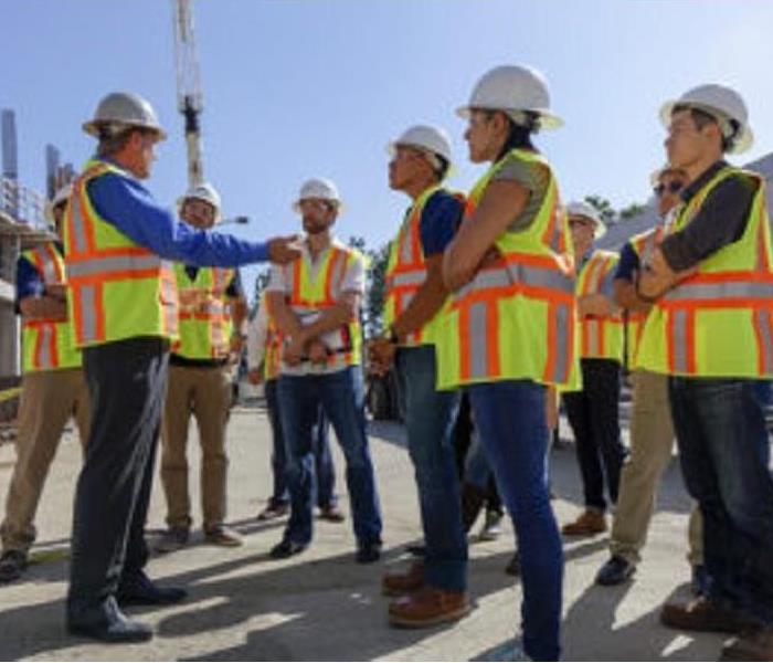 group of construction workers standing around manager, receiving instruction 